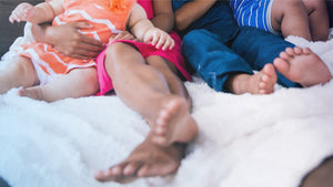 Close-up of a family's feet as they sit on a bed